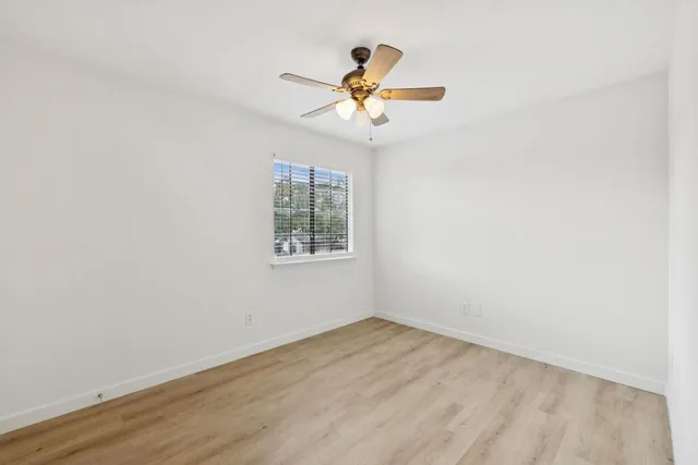 an empty room with a window and a fan