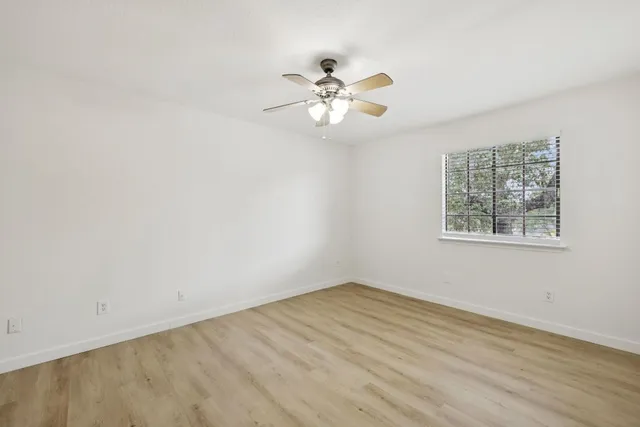 an empty room with a window and a fan