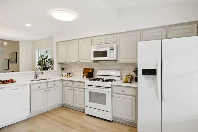 a kitchen with white cabinets and white appliances