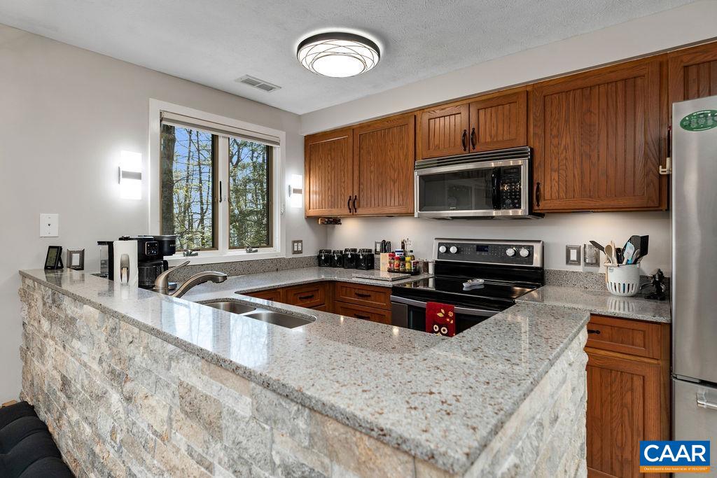 405 3 Ridges Roseland, VA 22967 - Photo 8 of 22 a kitchen with stainless steel appliances granite countertop a sink a stove a microwave and wooden cabinets