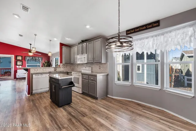 a kitchen with stainless steel appliances granite countertop a stove a sink dishwasher and a refrigerator with wooden floor