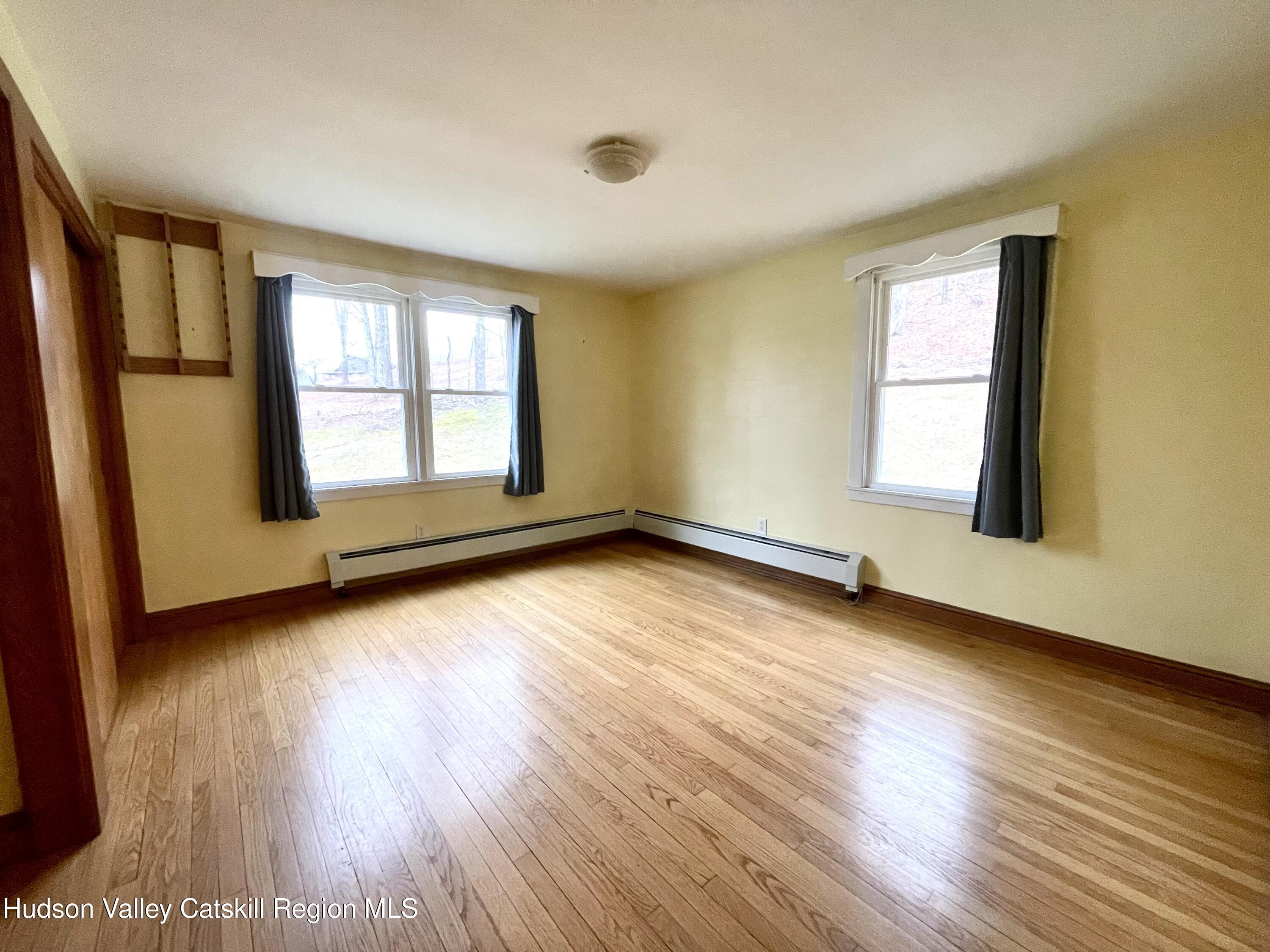 265 Scribner Hollow Road Hunter, NY 12442 - Photo 14 of 26 an empty room with wooden floor and windows