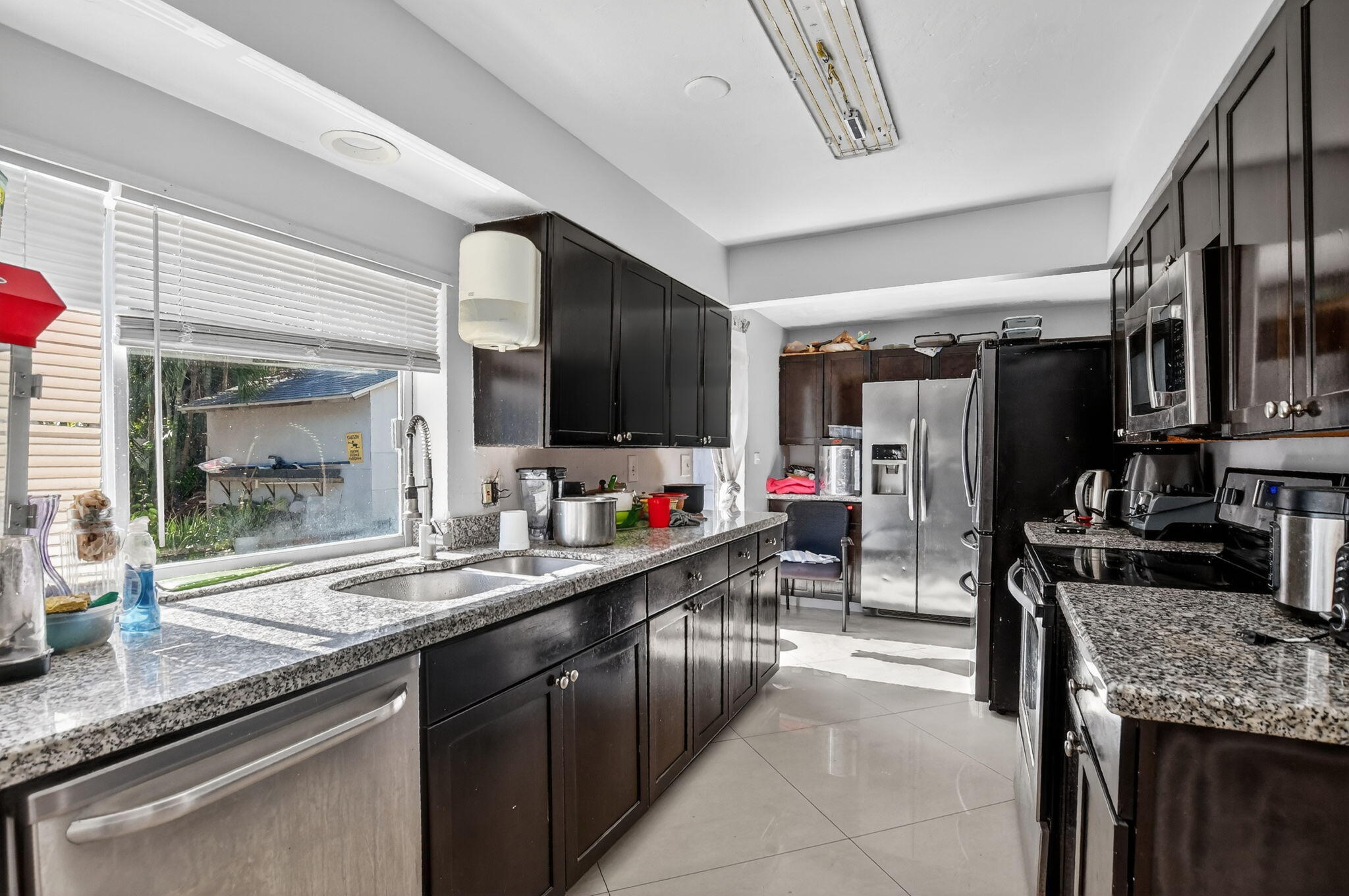 256 Southwest 11th Place Boca Raton, FL 33432 - Photo 17 of 43 a kitchen with stainless steel appliances kitchen island granite countertop a sink and cabinets