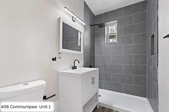 a bathroom with a toilet a sink a mirror and shower