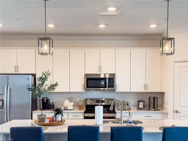 a kitchen with stainless steel appliances a stove a sink a refrigerator a microwave and white cabinets