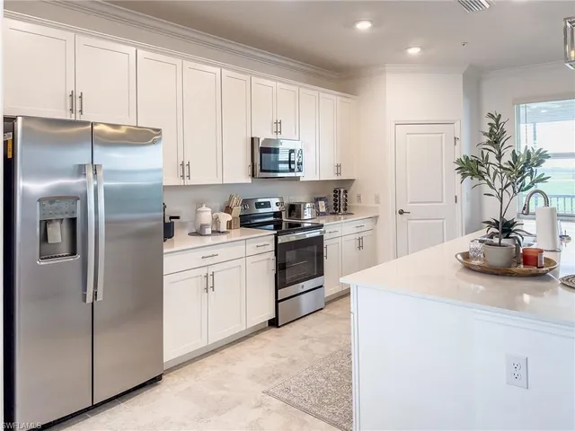 a kitchen with stainless steel appliances granite countertop a refrigerator a stove a sink dishwasher and white cabinets with wooden floor