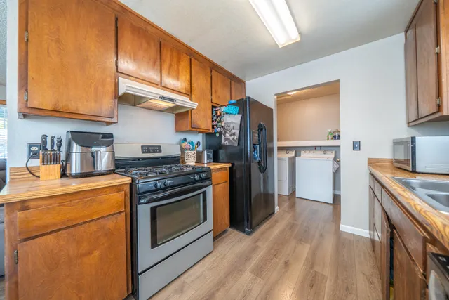 a kitchen with stainless steel appliances granite countertop a refrigerator a stove and a wooden floors