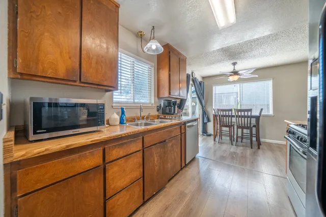 a kitchen with stainless steel appliances granite countertop wooden floors wooden cabinets a dining table and chairs