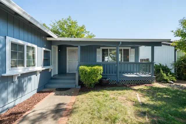 a front view of a house with a yard and potted plants