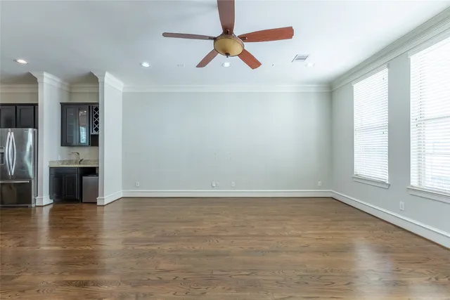 an empty room with wooden floor kitchen view and a window