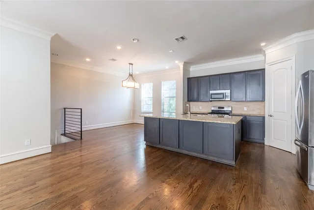 a kitchen with stainless steel appliances kitchen island wooden cabinets and wooden floor