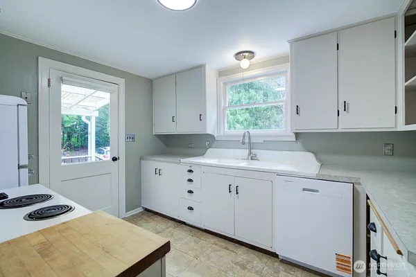 a kitchen with granite countertop a sink window and cabinets