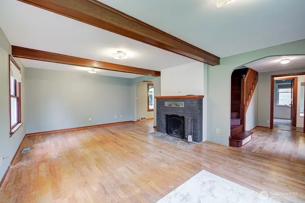 a view of an empty room with wooden floor fireplace and a window