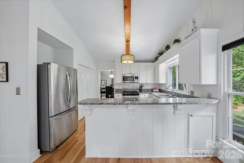 a kitchen with stainless steel appliances granite countertop a sink a refrigerator and a stove