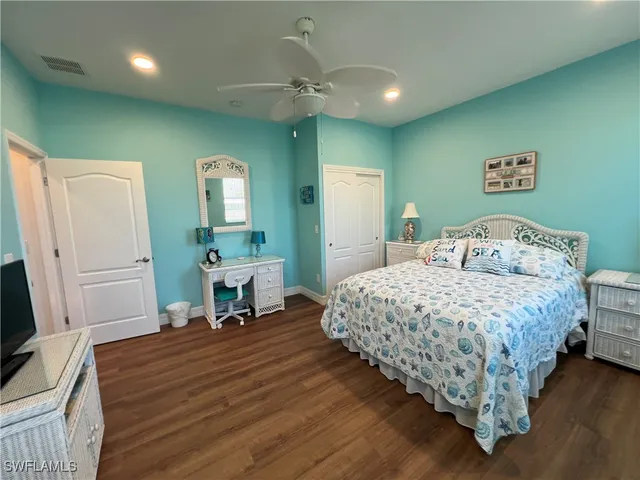 a bedroom with a bed and a large mirror on dresser with wooden floor