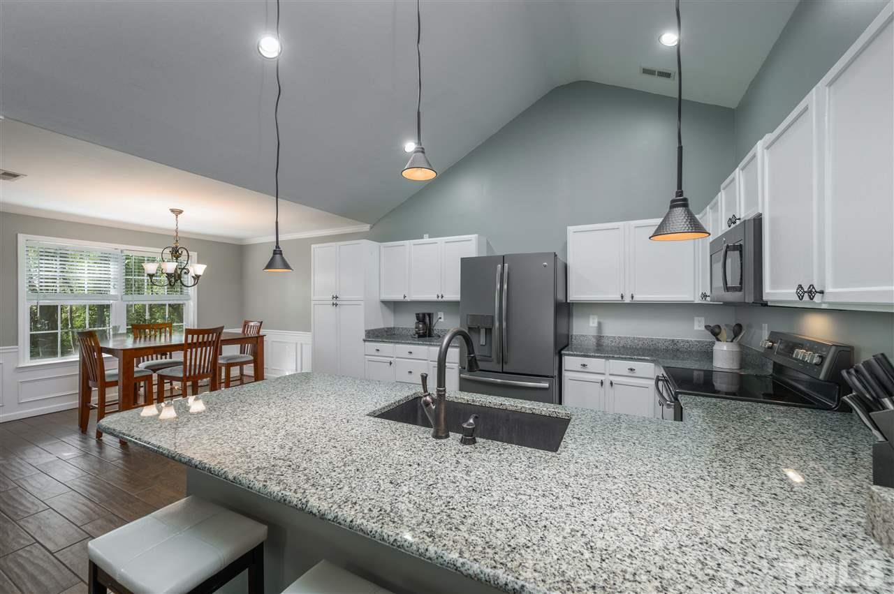 4520 Drewbridge Way Raleigh, NC 27604 - Photo 4 of 22 a kitchen with stainless steel appliances kitchen island granite countertop a refrigerator a stove a sink and a dining table with wooden floor