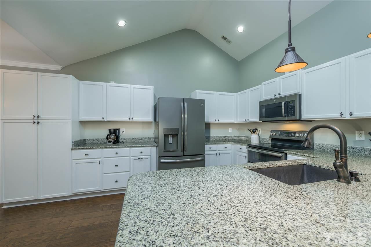 4520 Drewbridge Way Raleigh, NC 27604 - Photo 9 of 22 a kitchen with stainless steel appliances granite countertop a sink a stove a refrigerator a stove a oven with a dining table and chairs