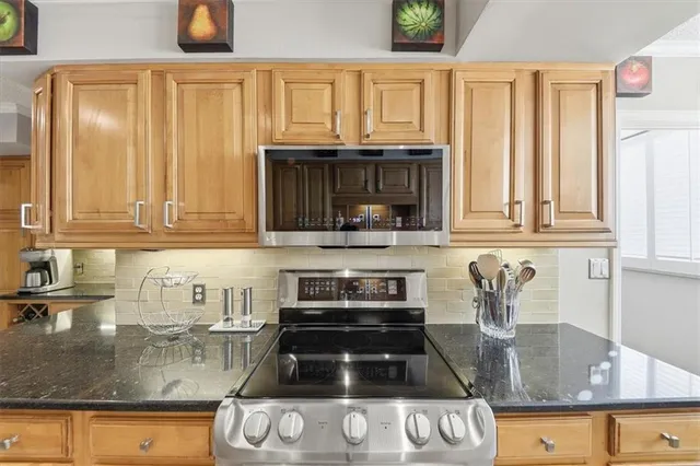 a kitchen with granite countertop a stove a sink and a microwave