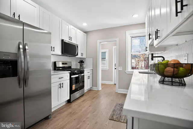 a kitchen with stainless steel appliances kitchen island granite countertop a refrigerator and a stove top oven