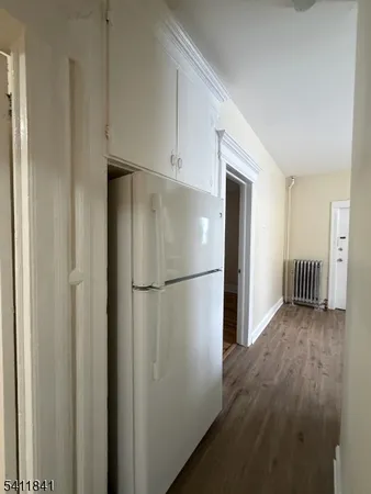 a view of a hallway with a refrigerator and wooden floor