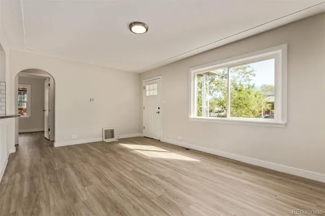 an empty room with wooden floor and windows