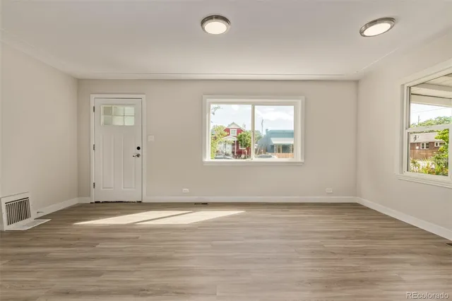 an empty room with wooden floor and windows