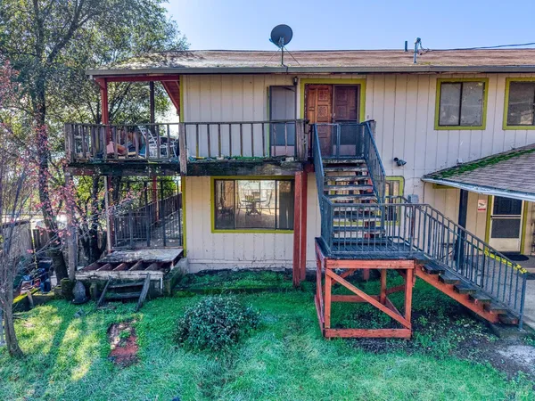 a backyard of a house with wooden fence and a large tree