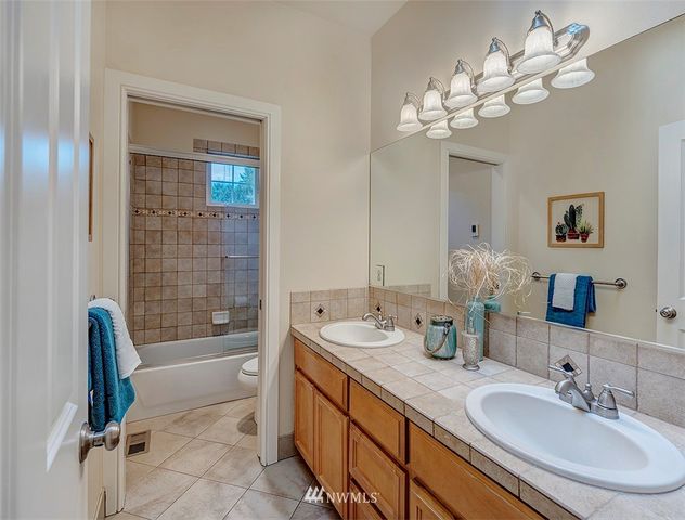 a spacious bathroom with a double vanity sink a tub and a mirror