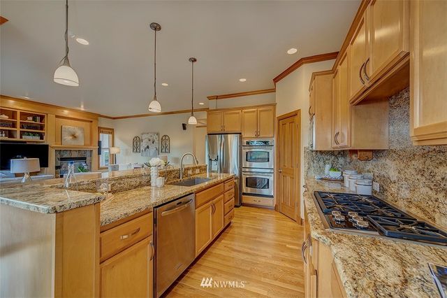 a kitchen with stainless steel appliances granite countertop a sink a stove and a wooden floors