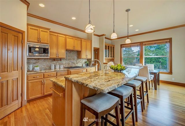a kitchen with stainless steel appliances granite countertop a stove a refrigerator a kitchen island a sink cabinets and a dining table