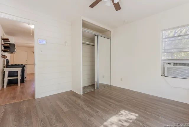 an empty room with wooden floor cabinet and windows
