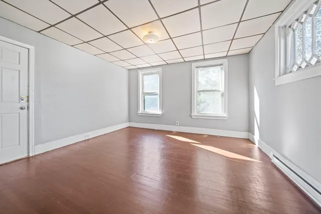 an empty room with wooden floor and windows with curtains