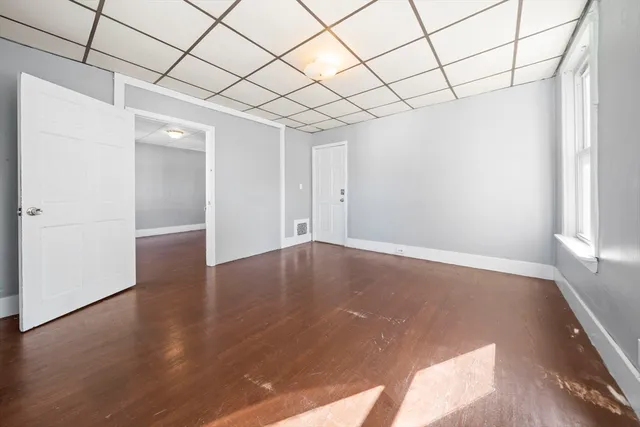 an empty room with wooden floor and natural light