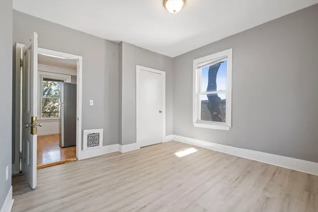 a view of an empty room with window and wooden floor