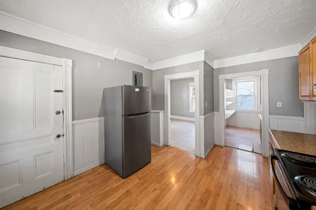 a kitchen with a refrigerator and wooden floor