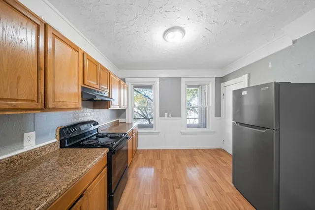 a kitchen with a refrigerator a stove a sink dishwasher and wooden cabinets with wooden floor