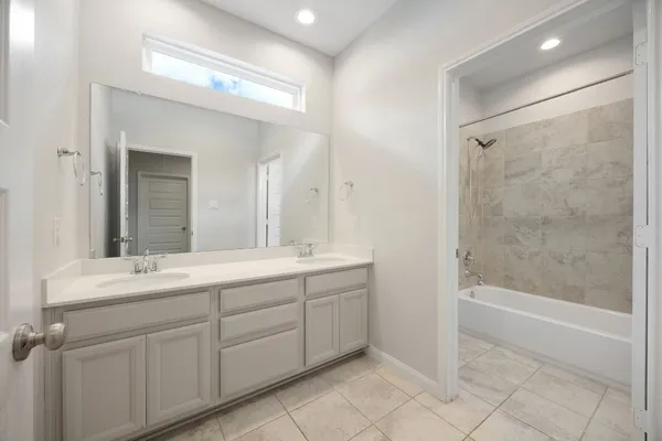 a bathroom with a double vanity sink mirror and a bathtub