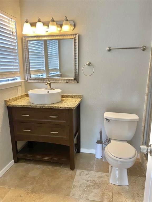 4404 Travis Country Circle, Unit G4 Austin, TX 78735 - Photo 7 of 15 A well-appointed bathroom with natural-toned tile flooring and a vanity featuring granite counters.