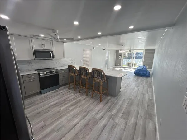 a kitchen with stainless steel appliances kitchen island granite countertop a stove a sink and a refrigerator with wooden floor