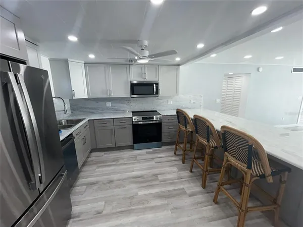 a kitchen with stainless steel appliances granite countertop a refrigerator a stove a sink a dining table and chairs