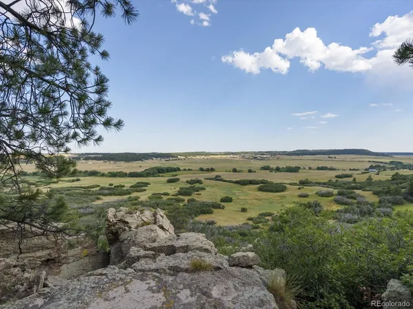 a white house with a large pool and lawn chairs next to a yard