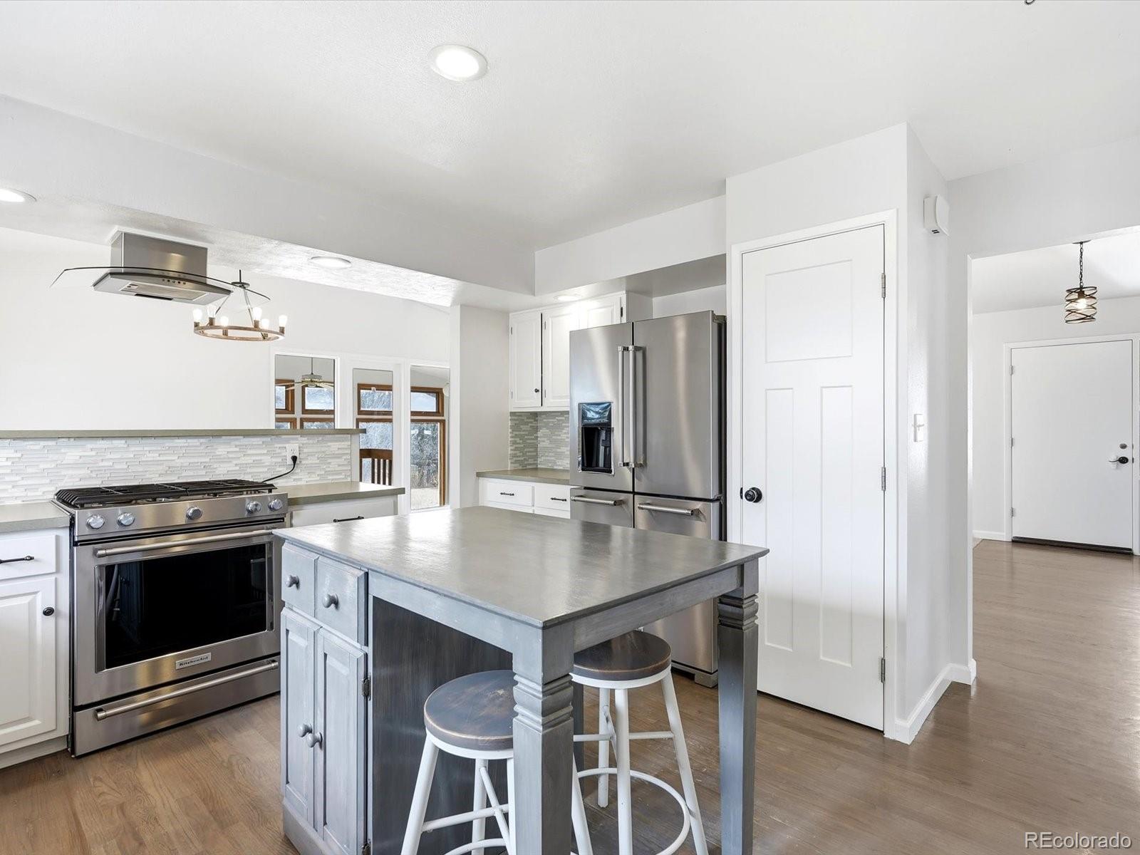 7750 East Greenland Road Franktown, CO 80116 - Photo 23 of 48 a kitchen with stainless steel appliances a stove a refrigerator and a fireplace