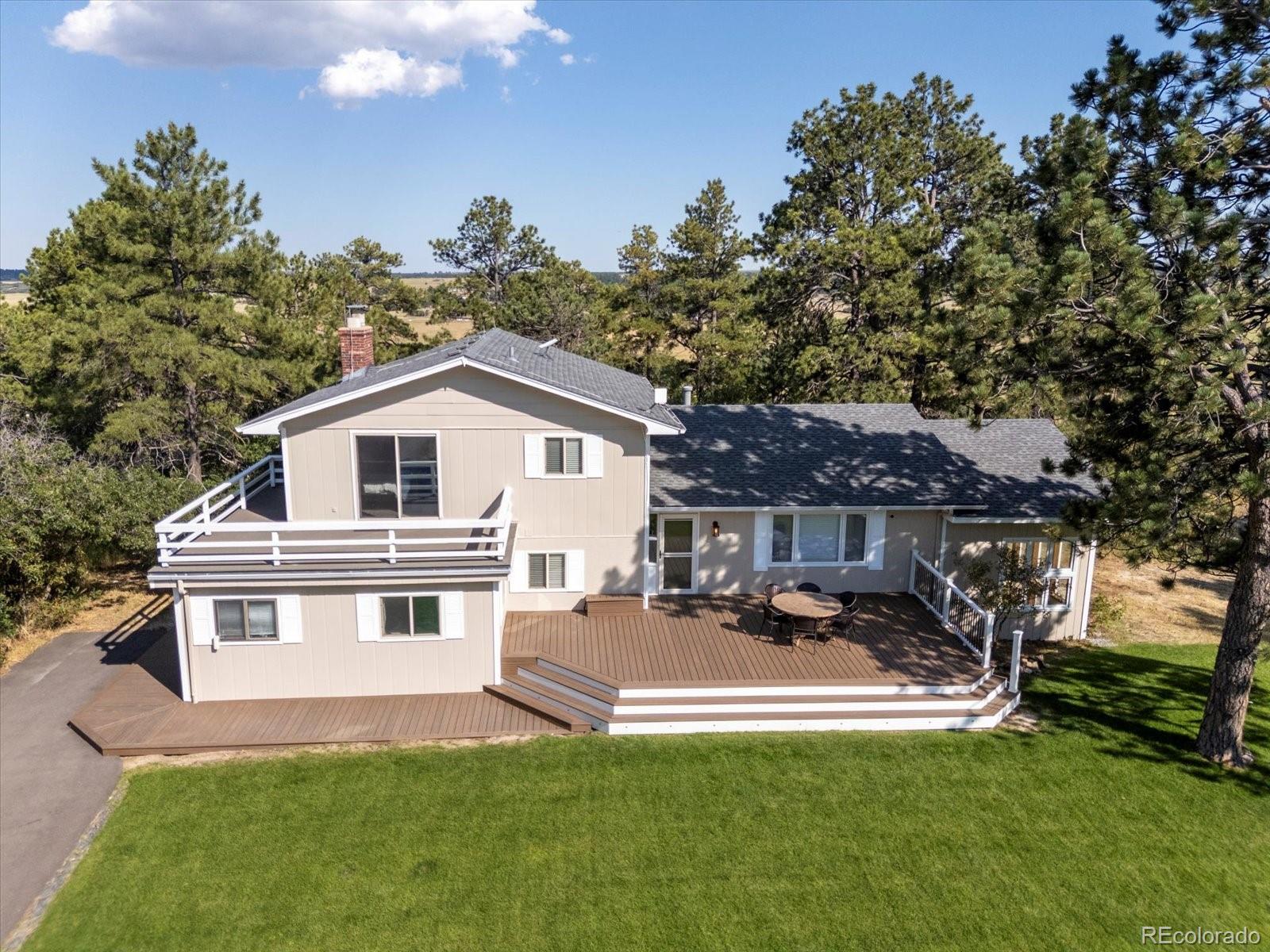 7750 East Greenland Road Franktown, CO 80116 - Photo 3 of 48 a white house with a large pool and lawn chairs next to a yard