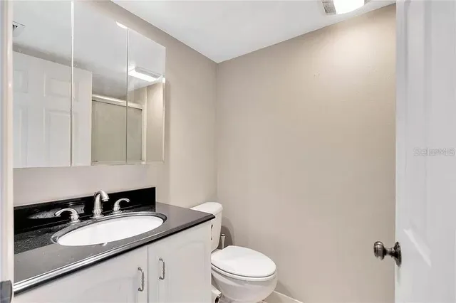 a bathroom with a granite countertop sink mirror vanity and toilet