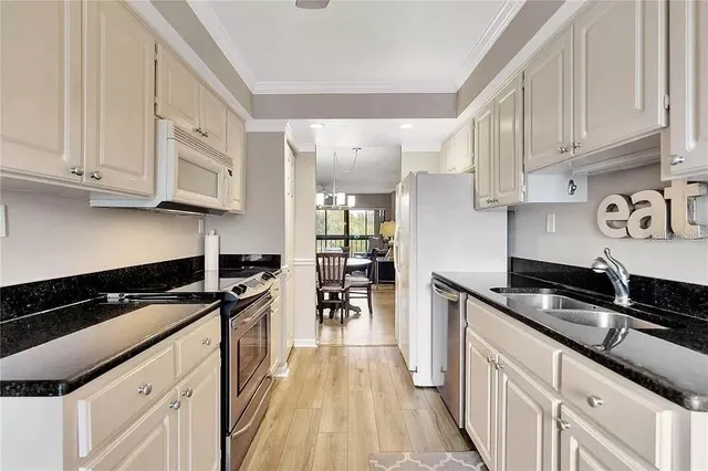 a kitchen with granite countertop a stove a sink a refrigerator and cabinets