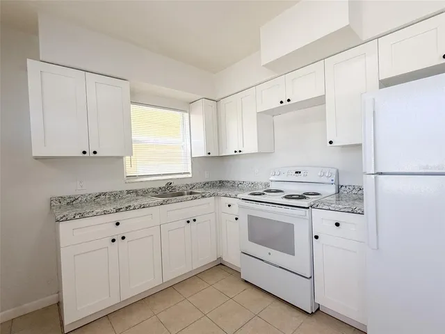 a kitchen with granite countertop white cabinets and white appliances