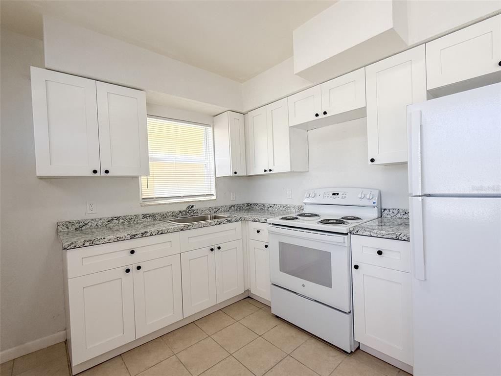 111 177th Avenue West, Unit 3 Redington Shores, FL 33708 - Photo 6 of 16 a kitchen with granite countertop white cabinets and white appliances