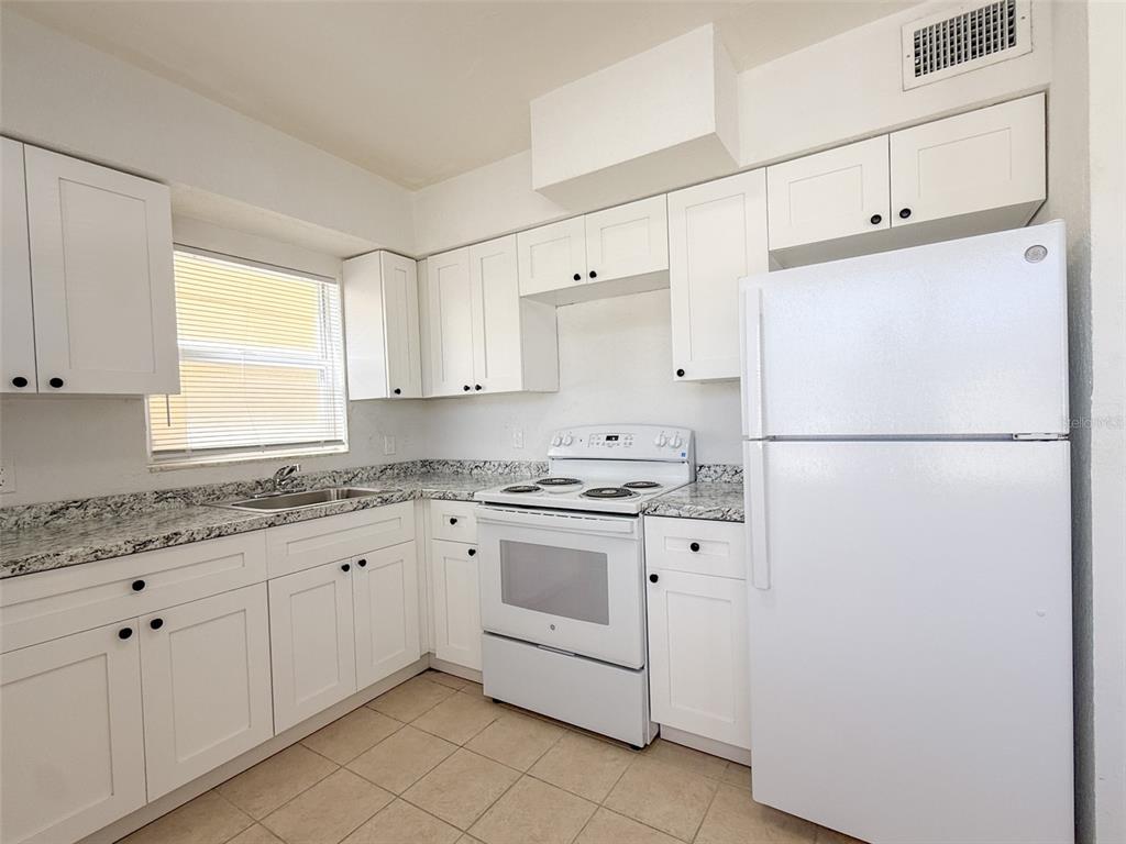 111 177th Avenue West, Unit 3 Redington Shores, FL 33708 - Photo 7 of 16 a kitchen with granite countertop cabinets appliances a sink and a window