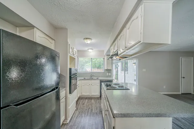 a kitchen with stainless steel appliances granite countertop a refrigerator a stove and a sink