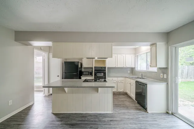 a large kitchen with stainless steel appliances a large counter top and a wooden floors